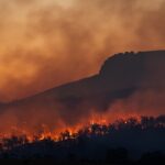 wildfire burning across hillside at dusk