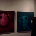 A woman standing in front of three paintings on a wall