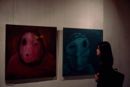 A woman standing in front of three paintings on a wall