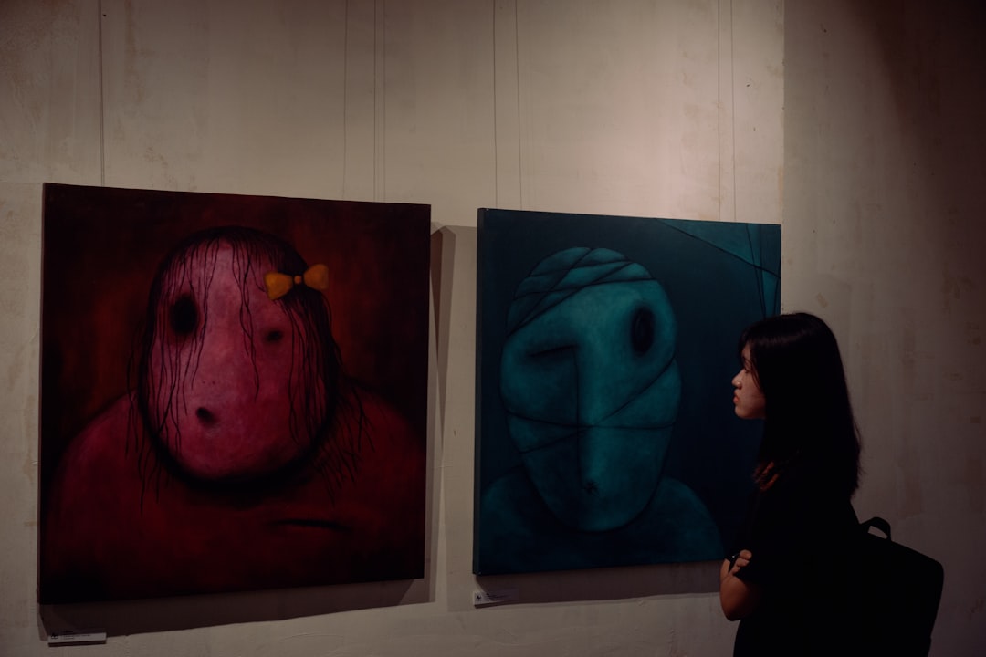 A woman standing in front of three paintings on a wall