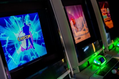 Row of glowing arcade game machines in darkness