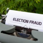 a close up of a typewriter with a paper that reads election fraud