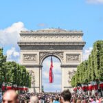 a large group of people in front of a large stone arch with Arc de Triomphe in the background