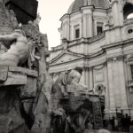 a black and white photo of a fountain in front of a building
