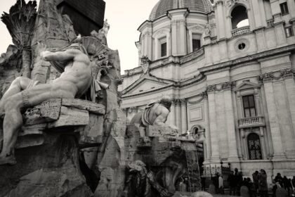 a black and white photo of a fountain in front of a building