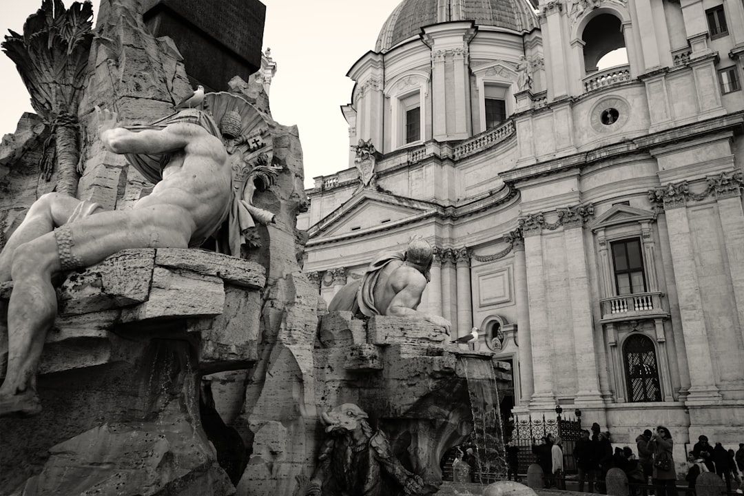 a black and white photo of a fountain in front of a building