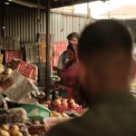 a group of people standing around a fruit stand