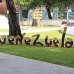 a sign that is in the grass near a tree