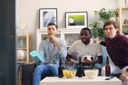 three men sitting on a couch in a living room