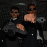 two men in suits are holding a gun