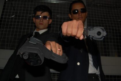two men in suits are holding a gun
