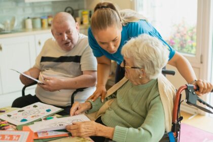 Caregiver assisting elderly couple with coloring