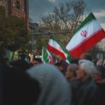 People holding iranian flags in a public gathering.