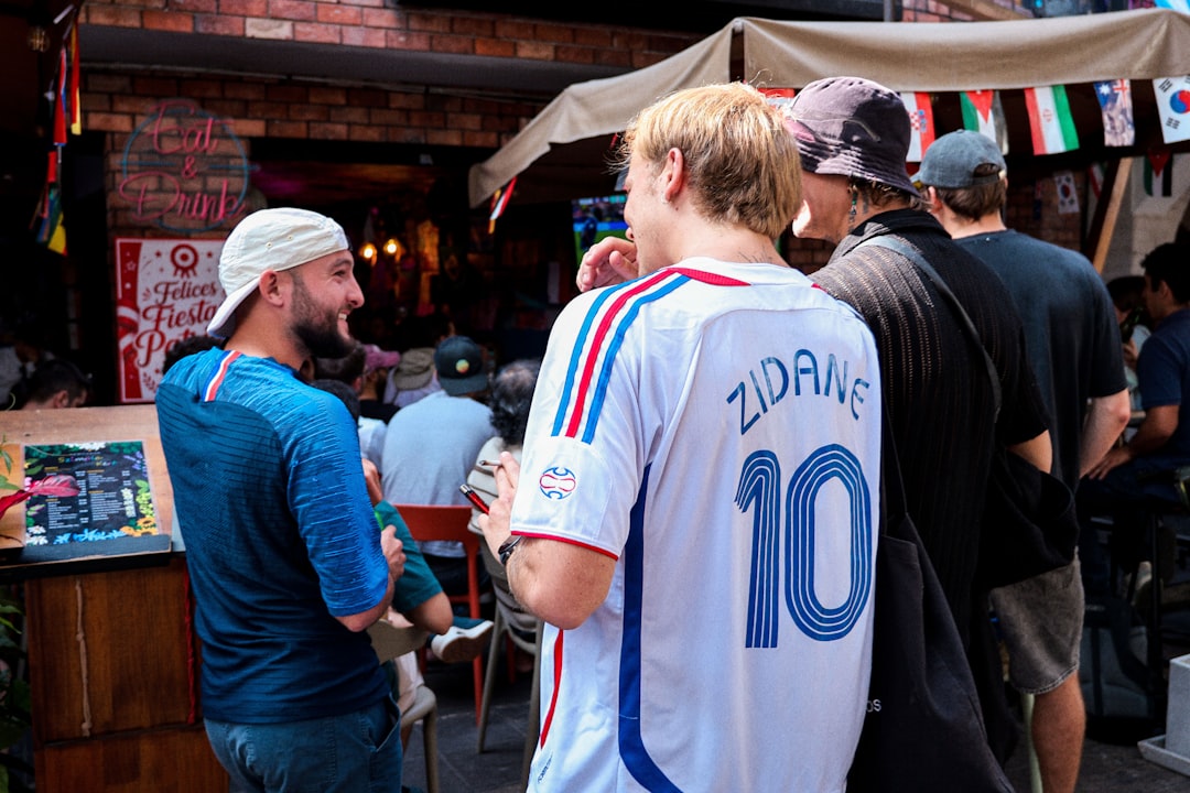 Men talking outdoors, one wearing a zidane soccer jersey.