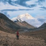 A lone hiker gazes at a snow-capped mountain