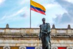 Colombian flag waves above a statue