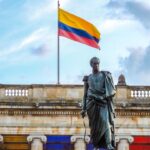 Colombian flag waves above a statue