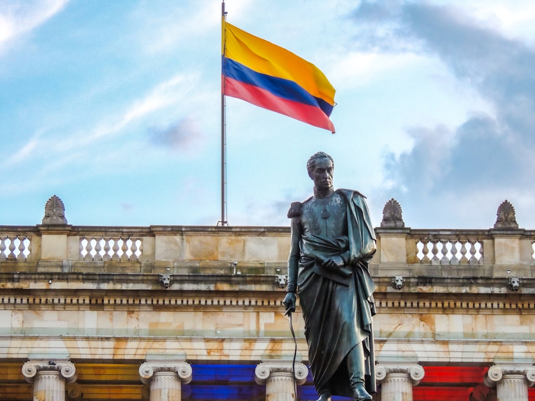 Colombian flag waves above a statue