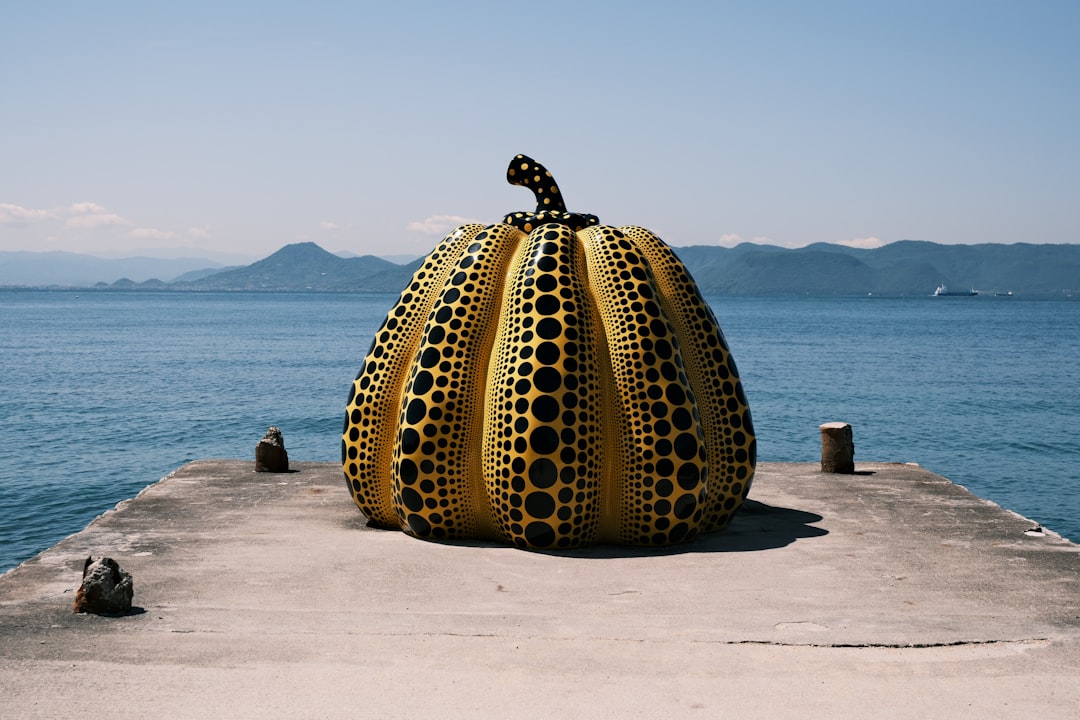 Giant yellow polka-dot pumpkin sculpture on a pier