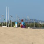 woman in red and blue dress sitting on brown sand during daytime