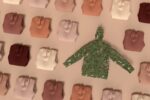 a paper cutout of a green shirt in front of a wall of colored paper