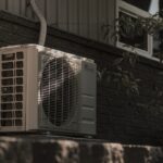 a white air conditioner sitting on top of a brick wall